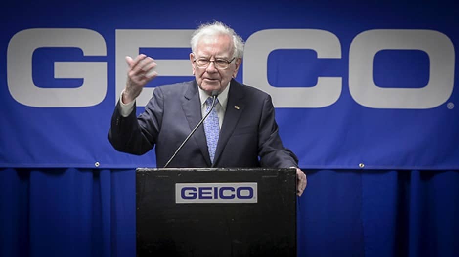 Warren Buffett in front of Geico logo